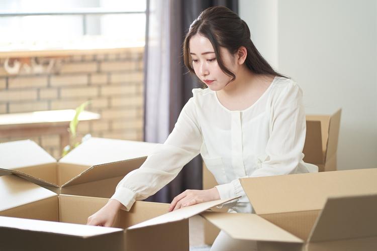 女性が引越し用に段ボールへ荷物を詰めている所