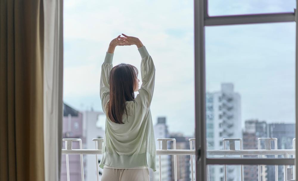 ベランダで伸びをする女性