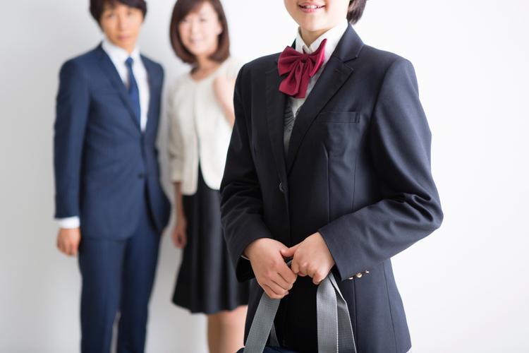 制服を着た女生徒と見守る両親