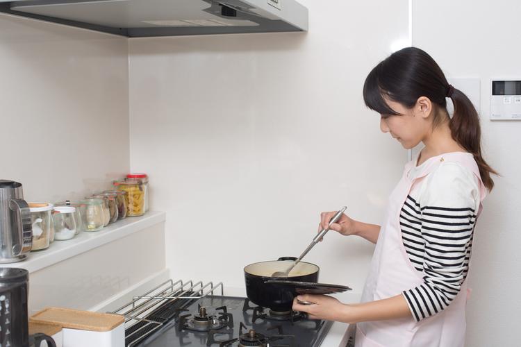 キッチンに立って調理している女子学生